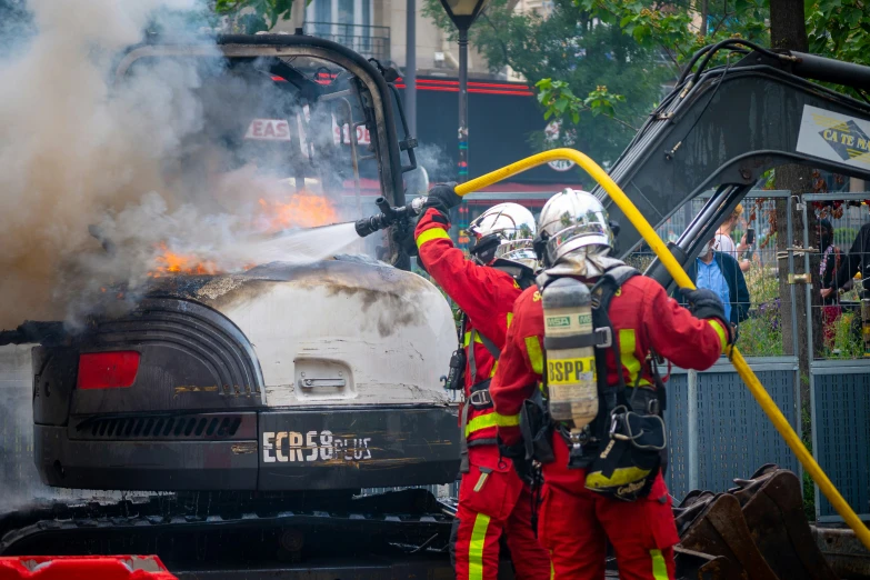 two firefighters extinguish the back of an old vehicle