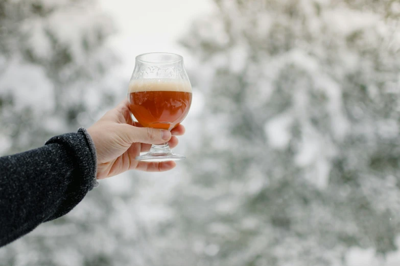 a hand holding a glass with a drink in it