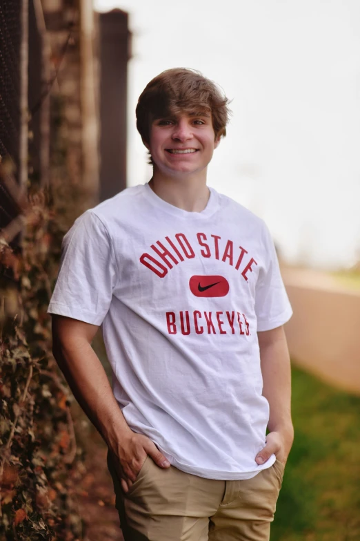 young man wearing t - shirt by a fence outside