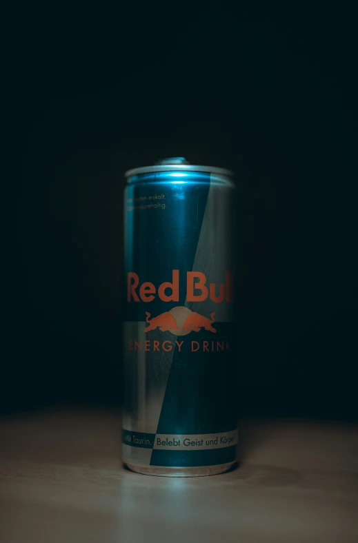a can of redbull energy drink sitting on a wooden table