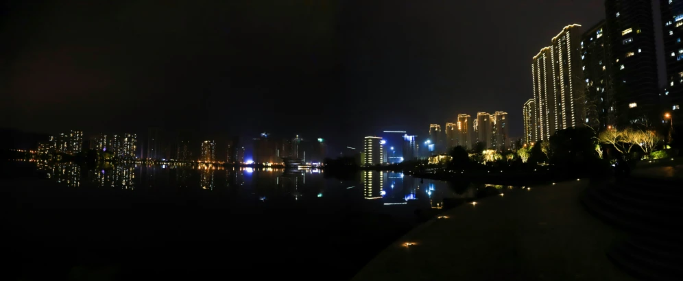 a very tall building with lights on it's sides near water