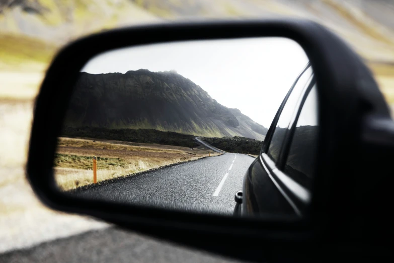 a view of a road from the rear view mirror of a vehicle