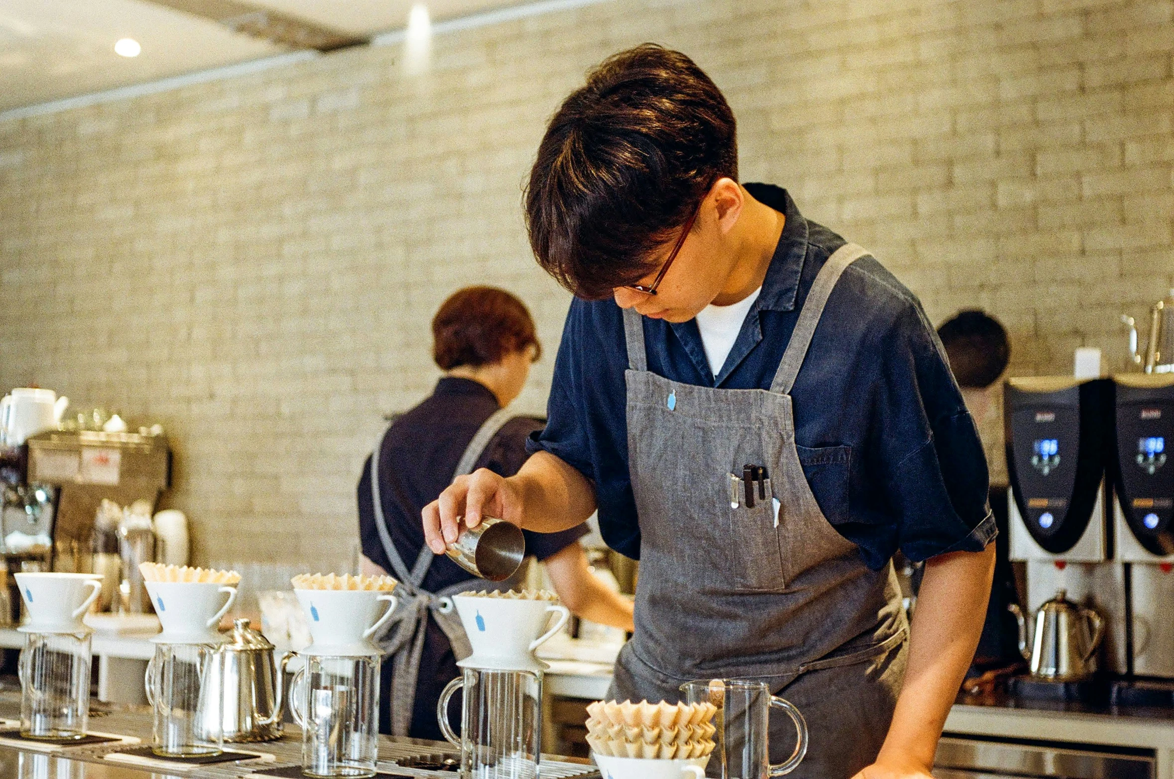 a chef in grey apron in kitchen making cupcakes