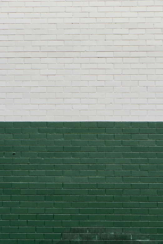 a lone bench is in front of a white brick wall