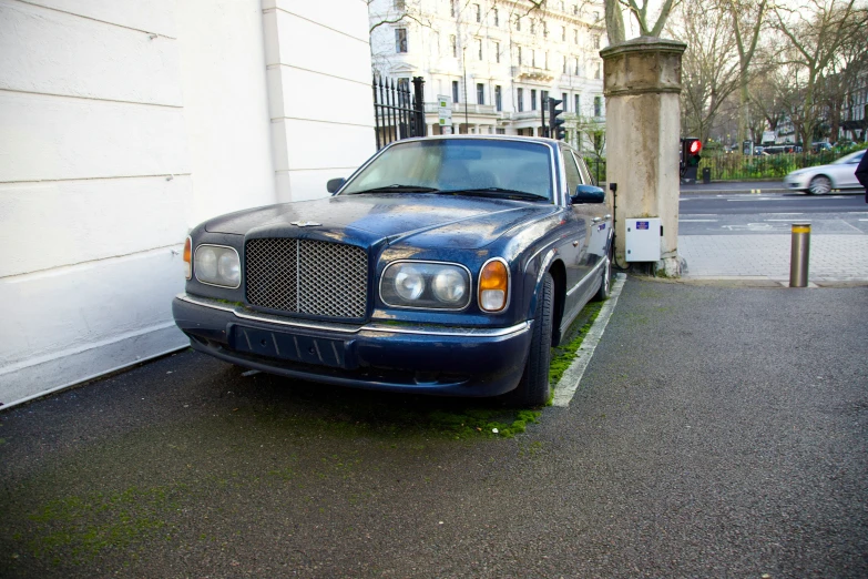 the blue sedan is parked on the side of the road