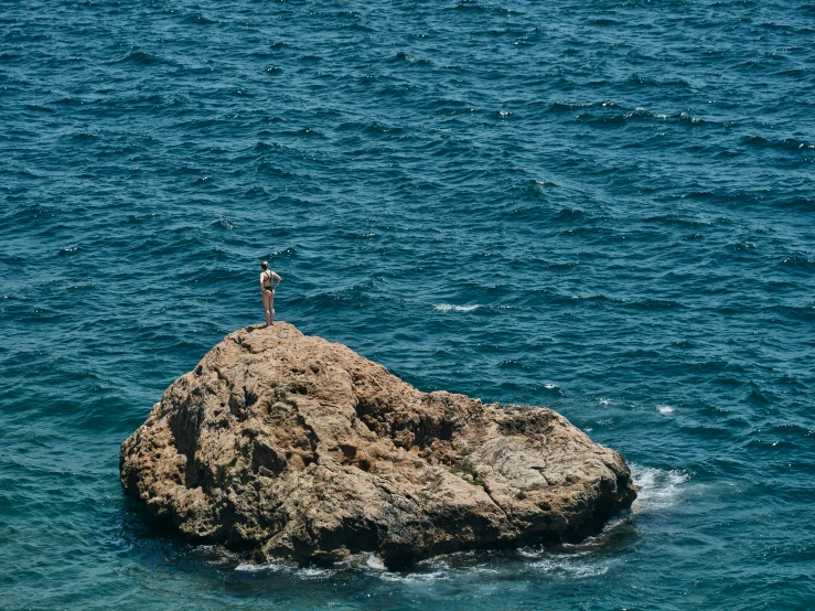 a man standing on a large rock that has some water around it