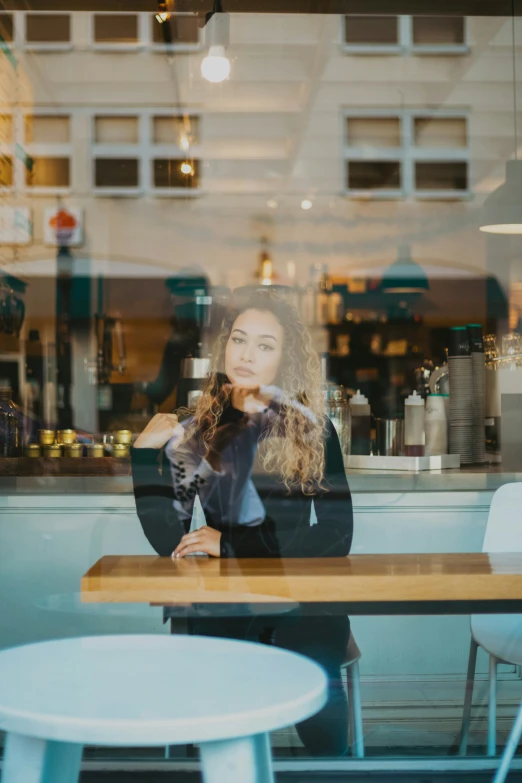 a woman is sitting at a table outside a store window