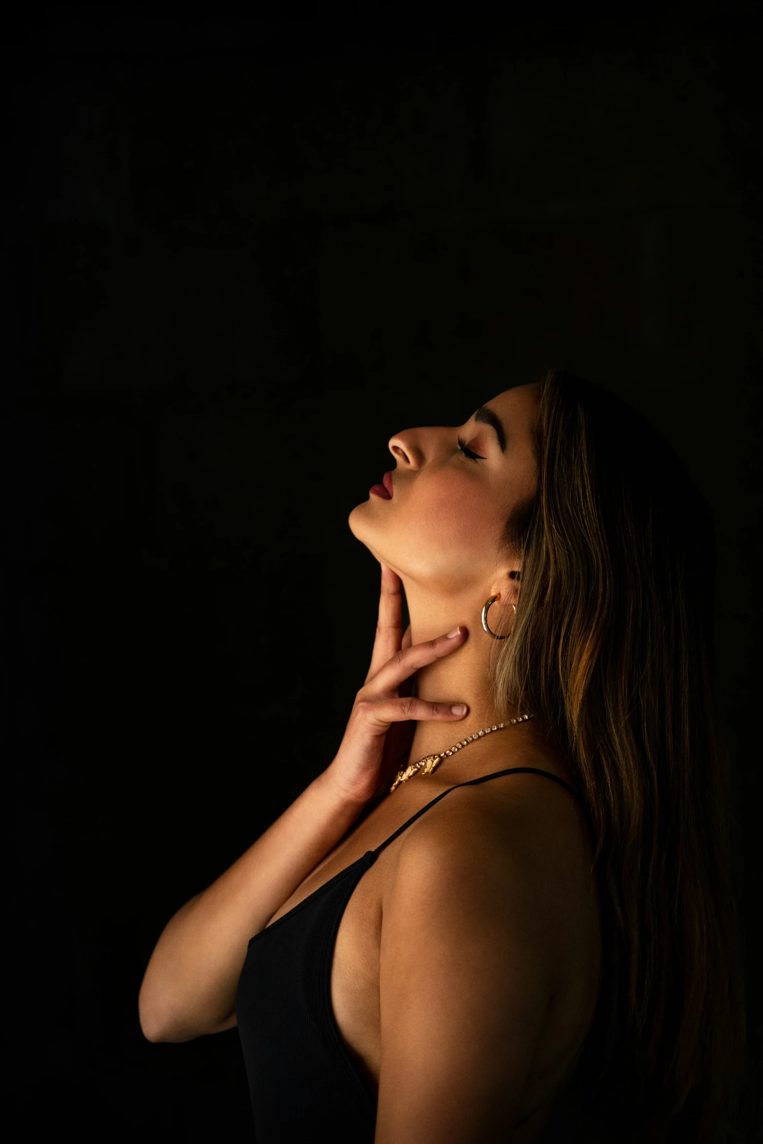 a woman wearing a necklace is posing in the dark