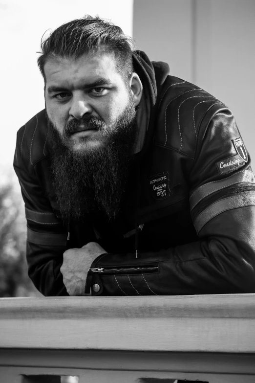a man with a beard and a jacket leans over a ledge