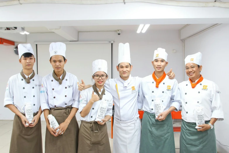 a group of chefs stand together wearing white uniforms