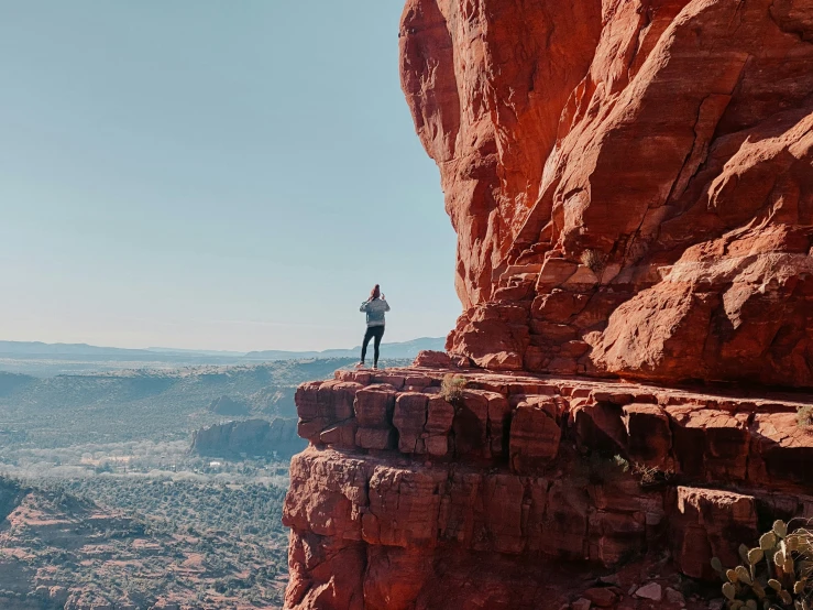 person standing on edge of rock face while looking at landscape