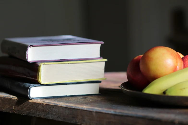 the fruits and books are stacked on a table