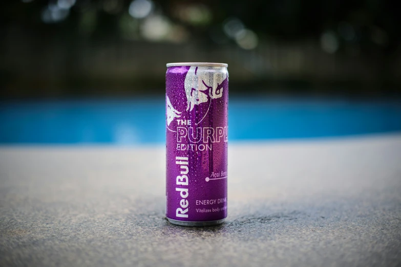 a can of beer is on a table next to a pool