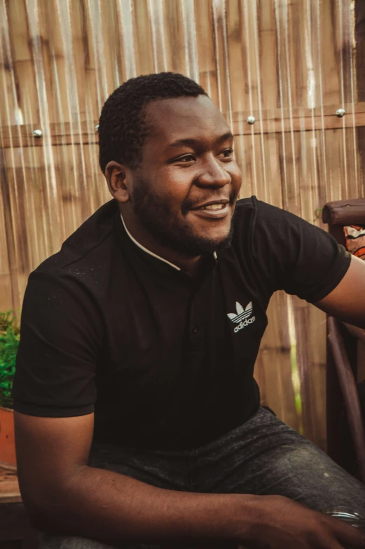 a black man smiling while sitting on a chair