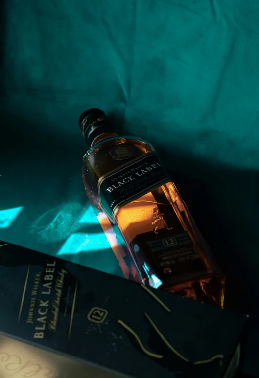 a glass bottle is next to a book on a blue fabric