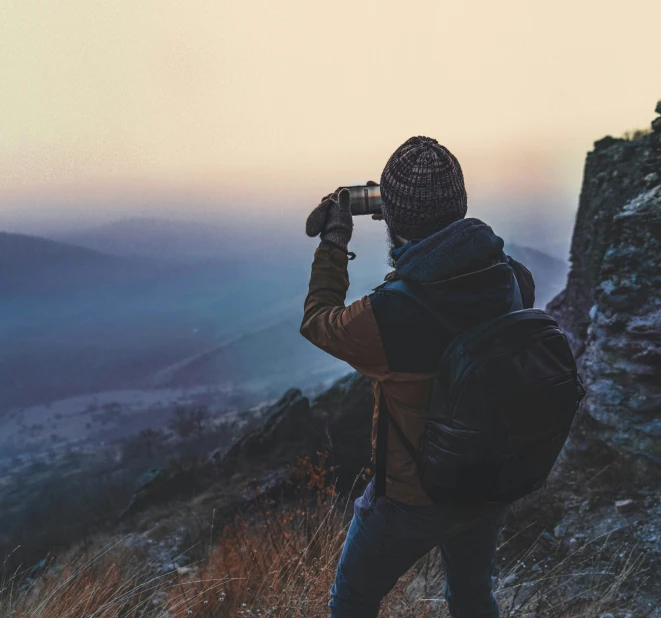 man standing in the wilderness taking pictures with his camera