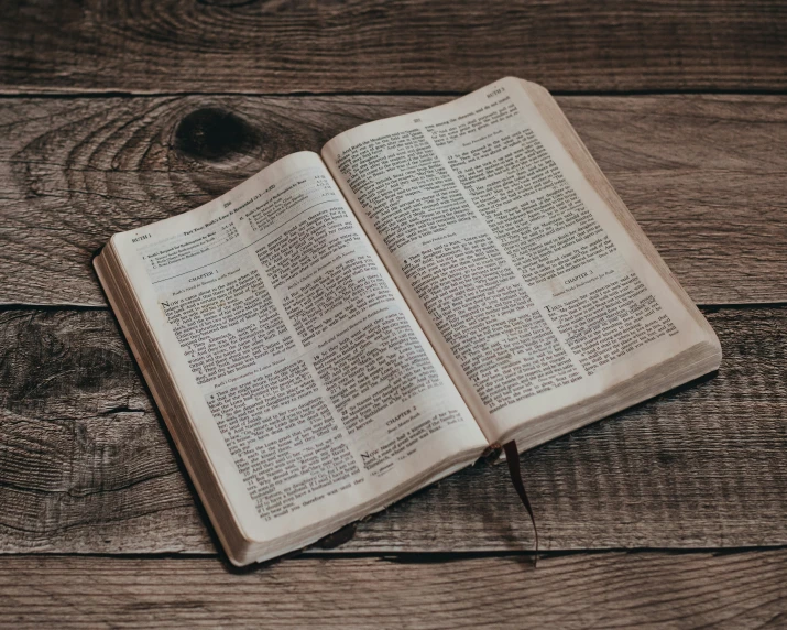 an open book on a wood table with writing on it