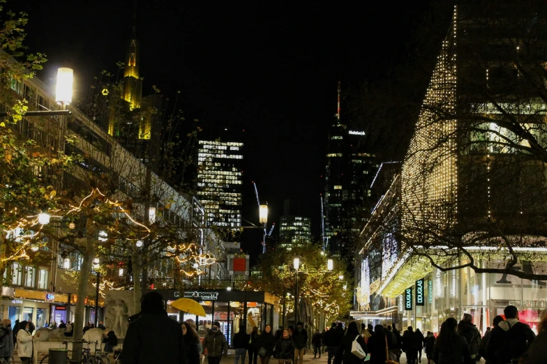 several people walk on an urban sidewalk at night