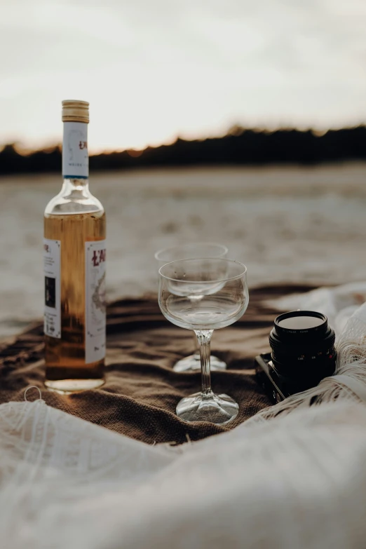 there is a bottle of liquor and a glass sitting on a blanket