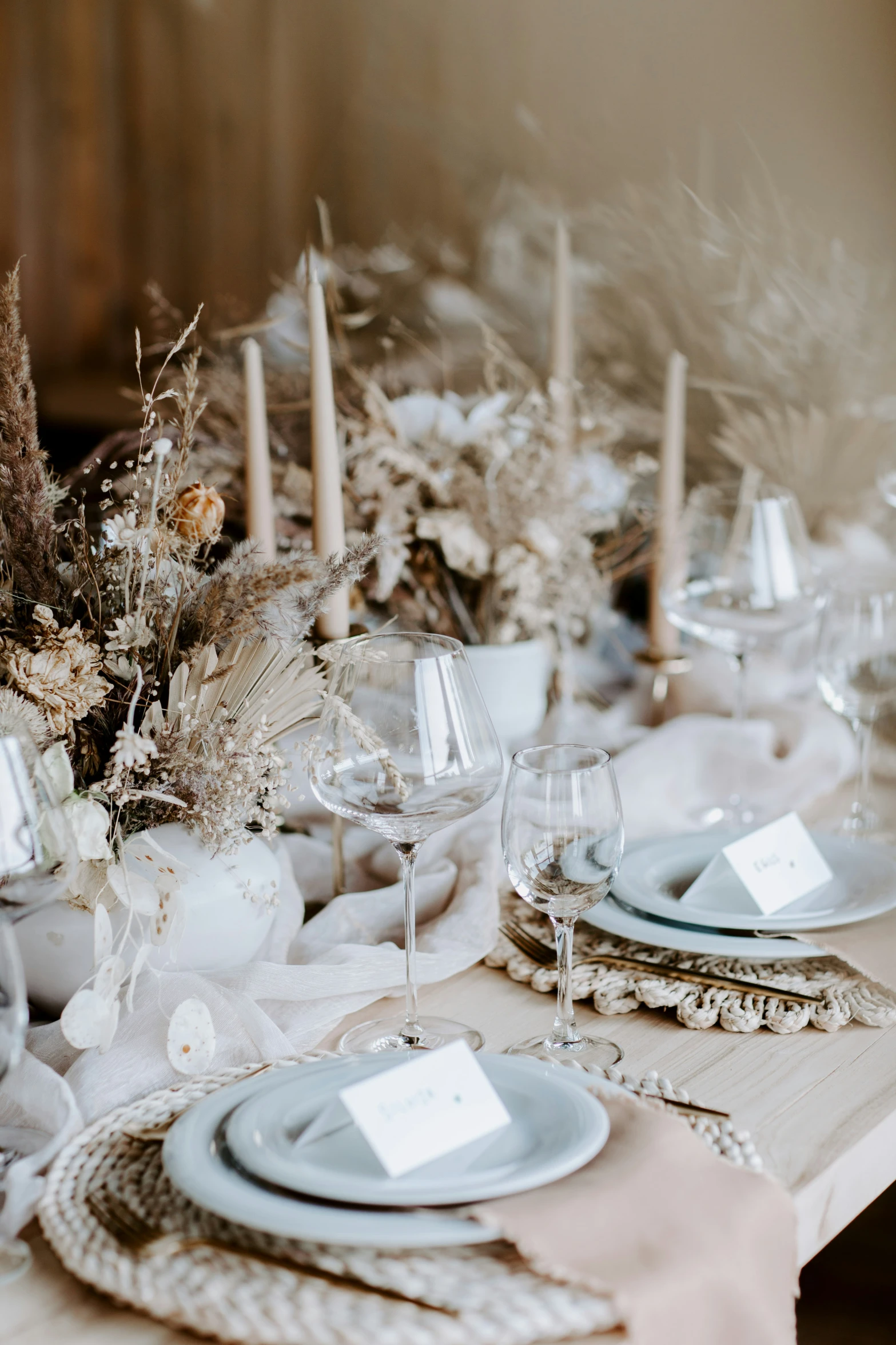 a white dinner table is set with candles and place settings