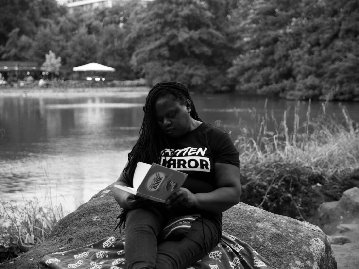 black and white po of a person reading on a rock