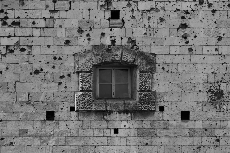 a brick wall with window, with a few holes on it