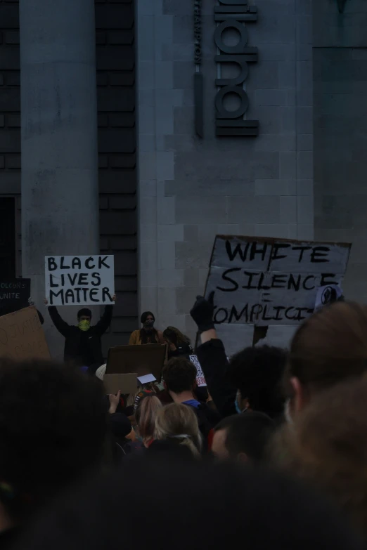 protesters are standing near a sign during a demonstration