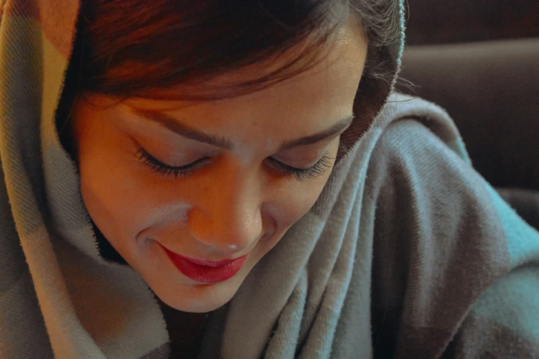 a lady sitting and smiling while looking at her cell phone