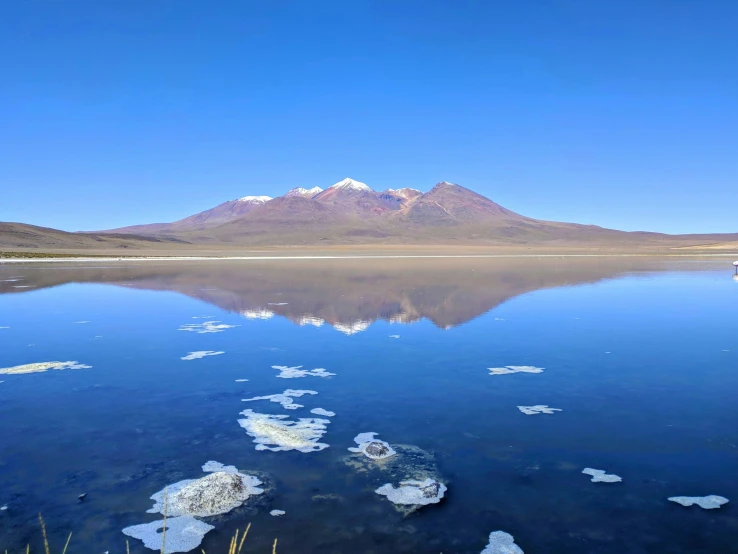 a lake with snow flakes on the surface and mountains in the background