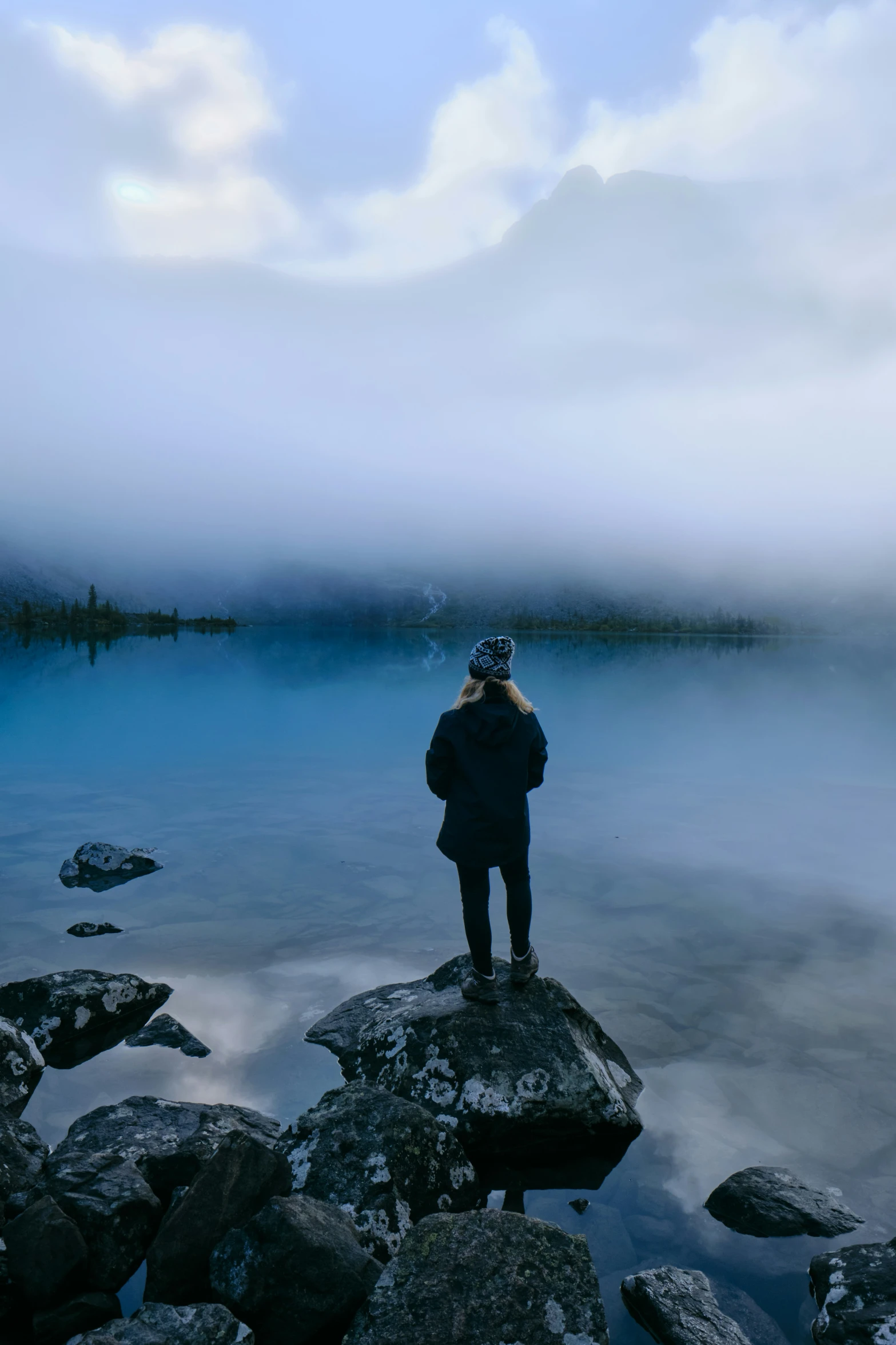 person standing on rock looking out at the water