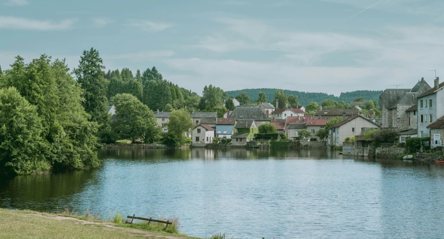 a lake with houses on the sides and a cloudy blue sky