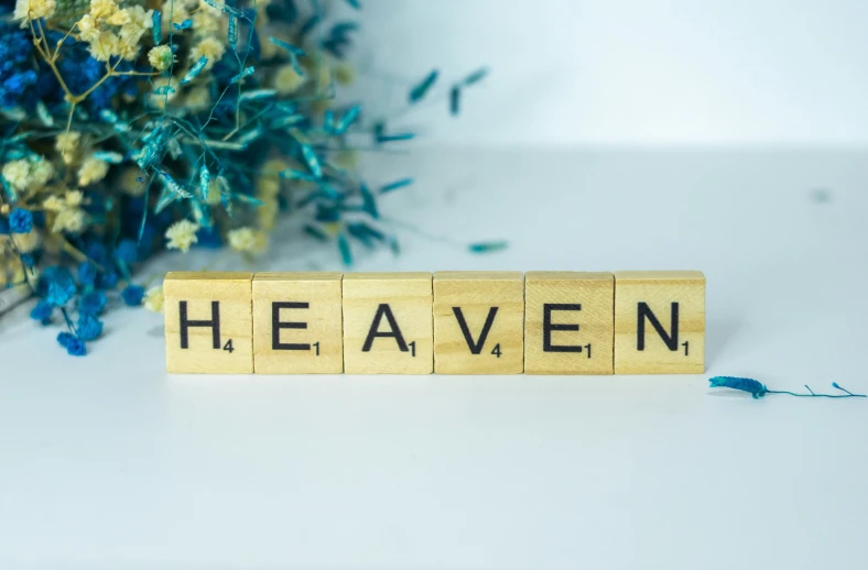 a wooden block that says heaven beside flowers