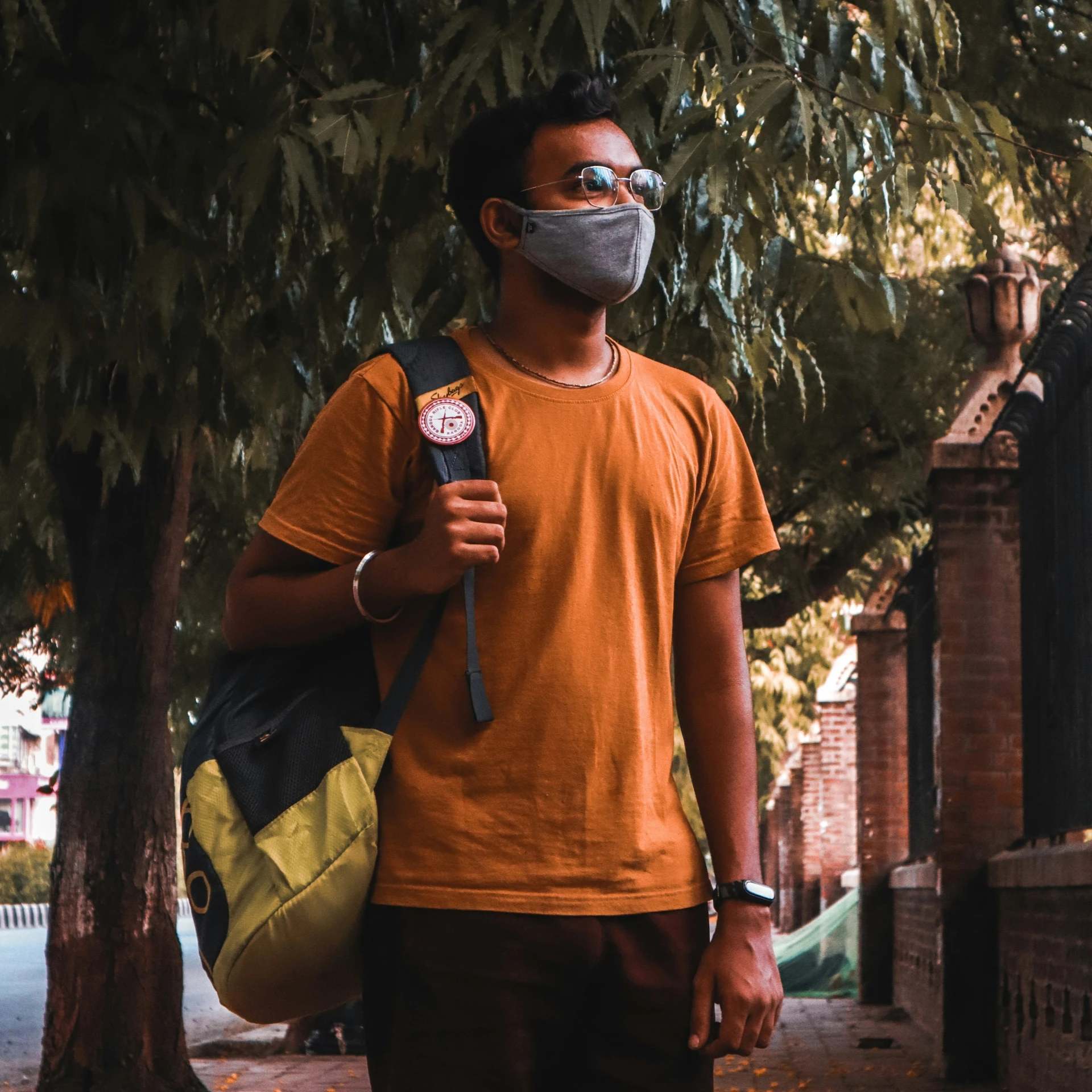 a man in an orange shirt and face mask holding a small object