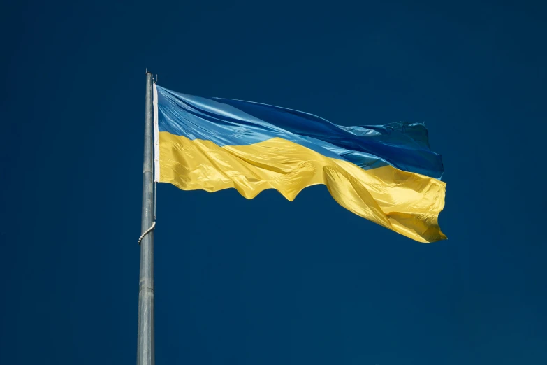 a flag waving in the wind on a blue sky day