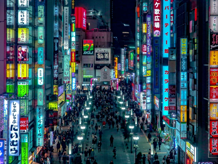 a crowded street lined with brightly lit signs at night