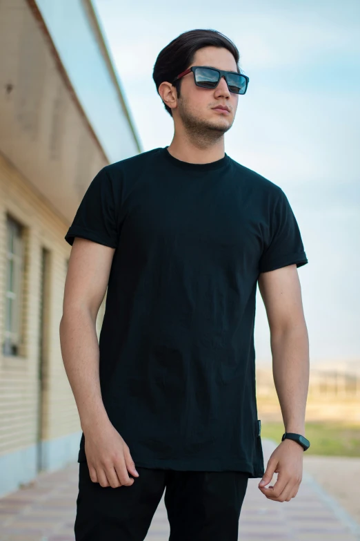 a young man wearing sunglasses standing outside of a building