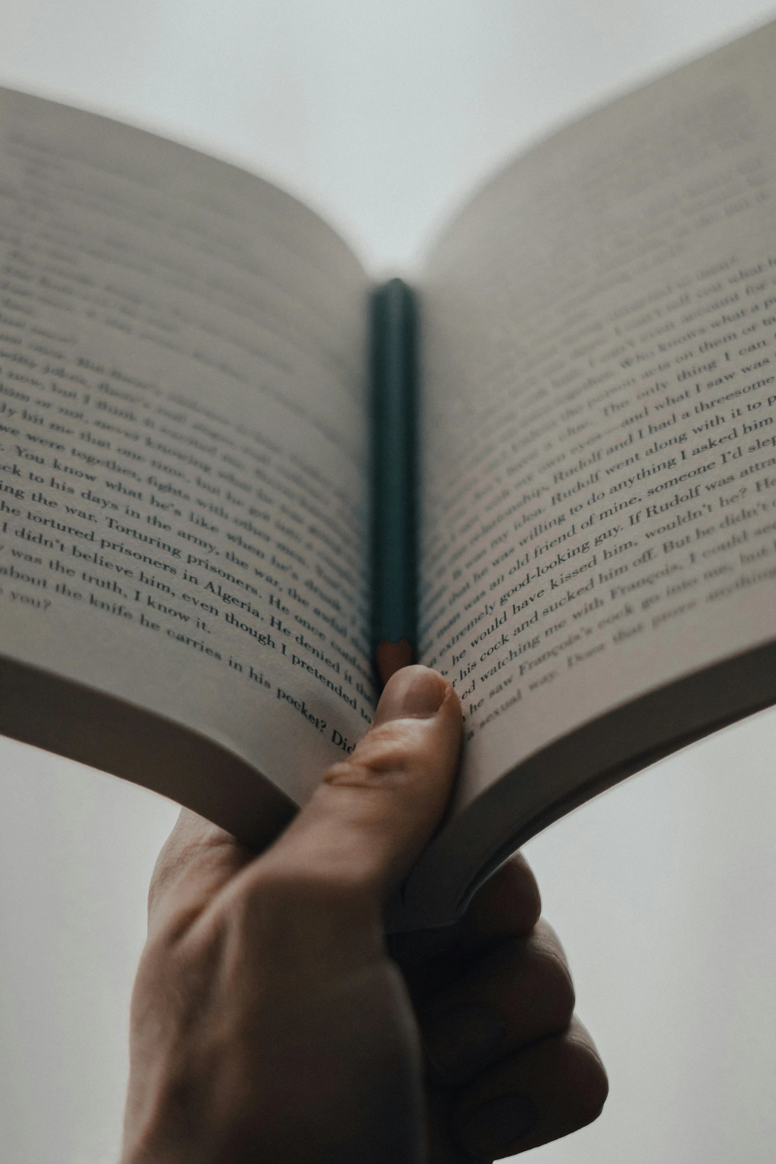 the image of a person's hand holding an open book