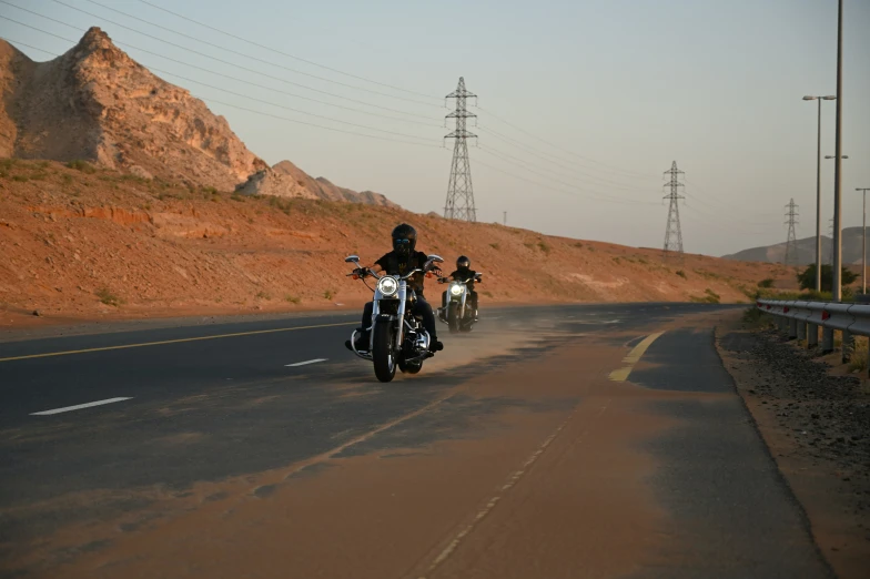 several motorcycles driving down a road in front of mountains