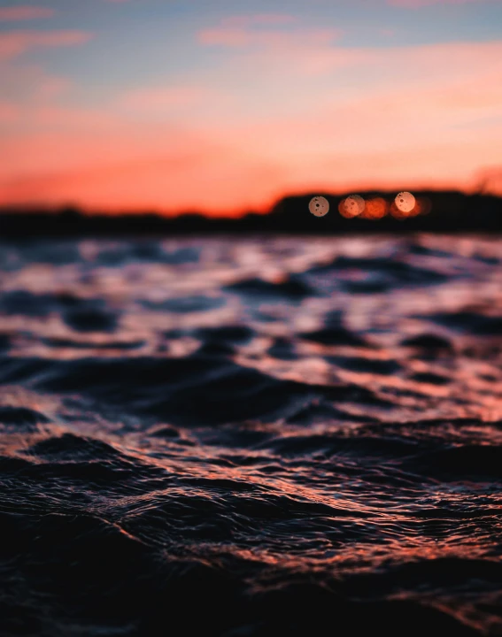 a sunset with blurred lights shining above water