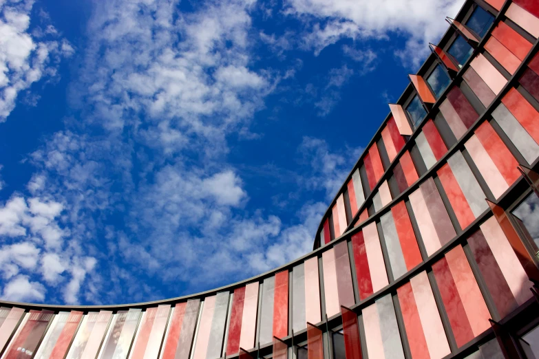 a curved building is decorated with striped red and blue glass