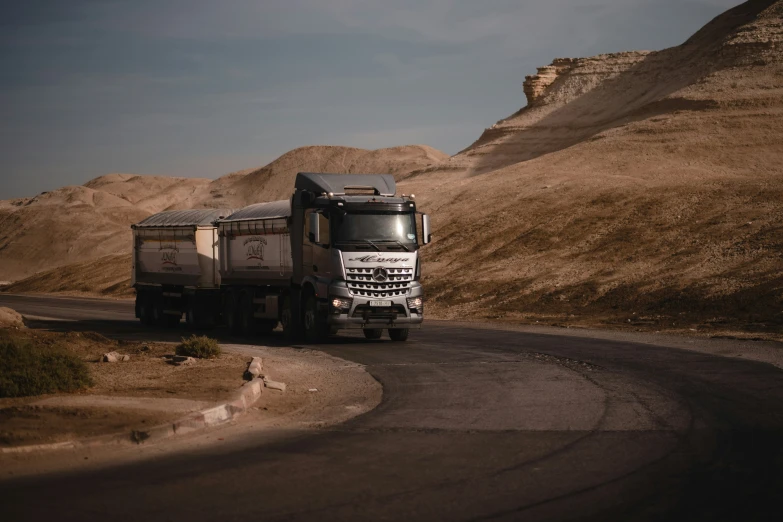 a truck driving down the road near a mountain