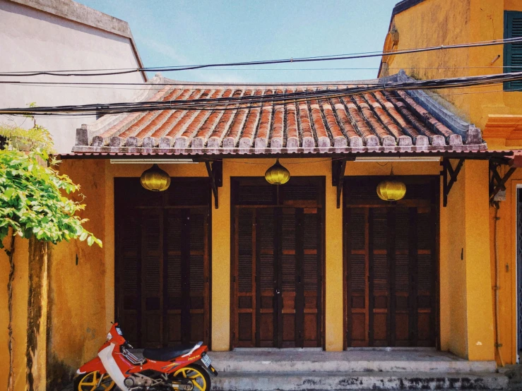 a motor bike sits parked in front of a yellow building