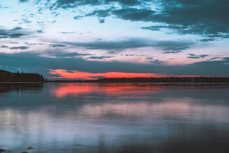 a calm lake with clouds at sunset or sunset