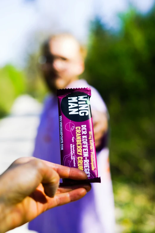 person holding up a bar that contains a bite of pink gum