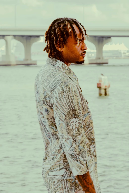 a young man standing in front of a body of water