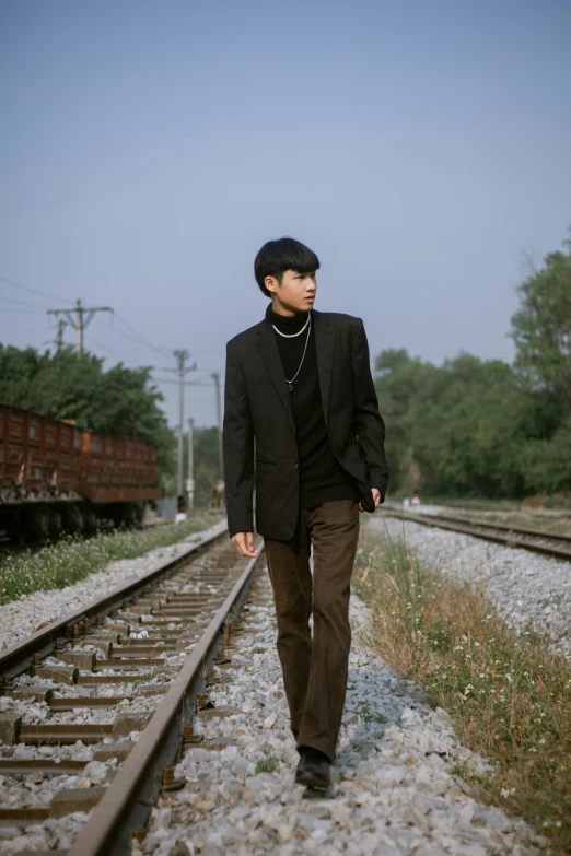 a man walking down the tracks near some grass