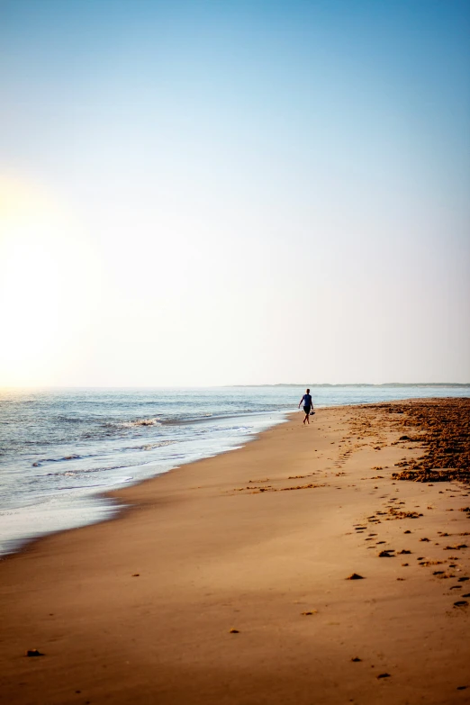 a person walking along the beach during sunrise