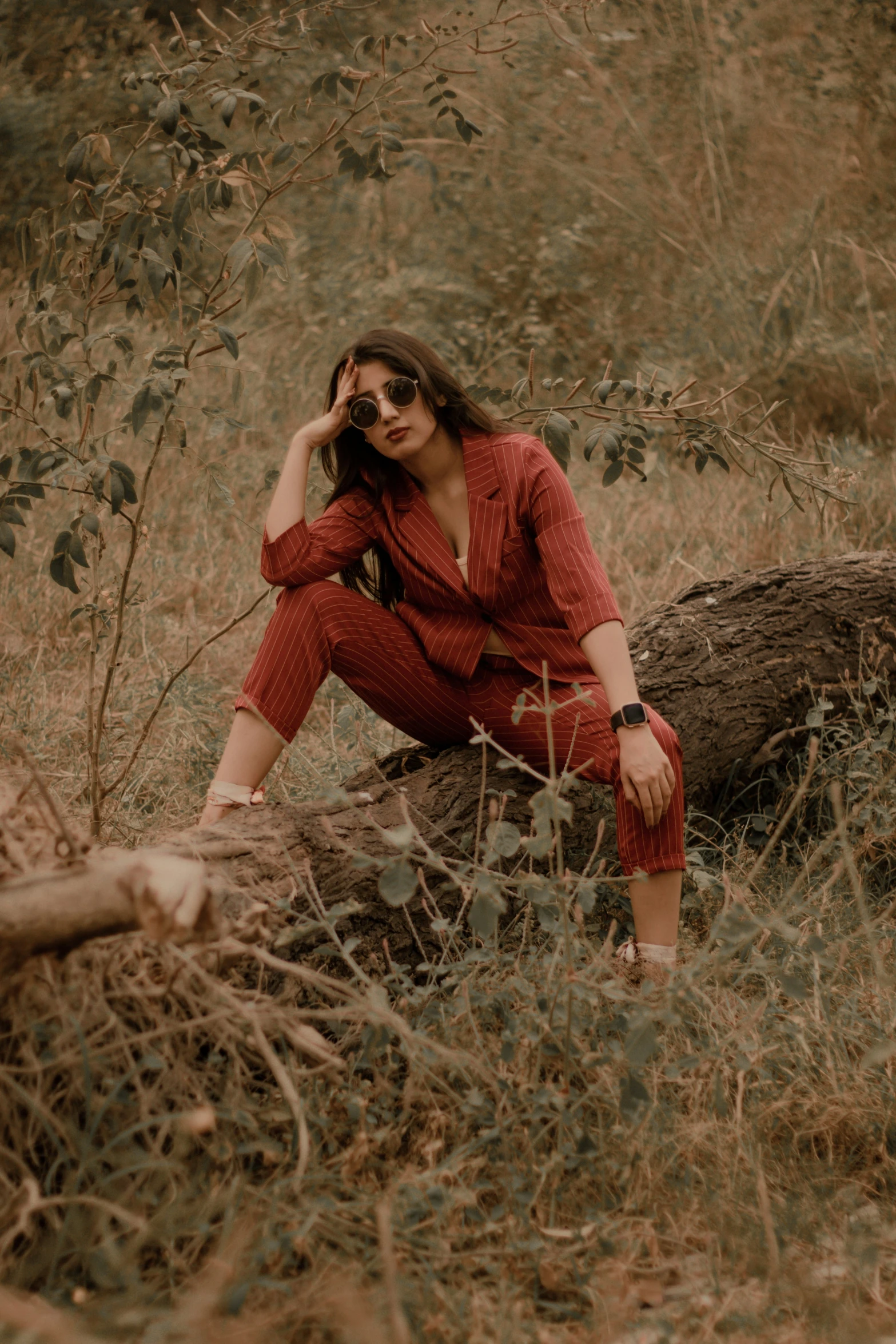 the woman is sitting on top of a log in the grass