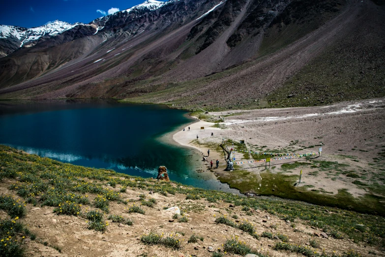 three people are walking in the distance towards a blue lake