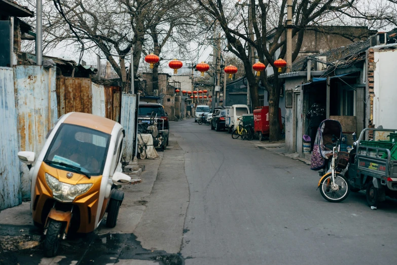 a small orange car parked on a narrow alley way